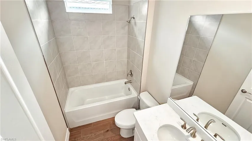 Full bathroom featuring vanity, tiled shower / bath, hardwood / wood-style flooring, and toilet