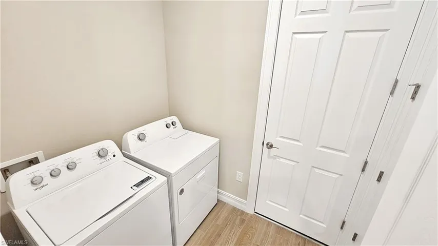 Washroom featuring washing machine and dryer and light hardwood / wood-style flooring