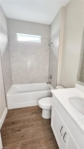Full bathroom with vanity, tiled shower / bath combo, and toilet