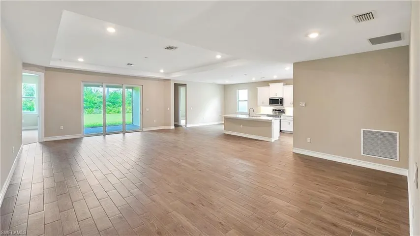Unfurnished living room with light hardwood / wood-style floors, sink, and a raised ceiling