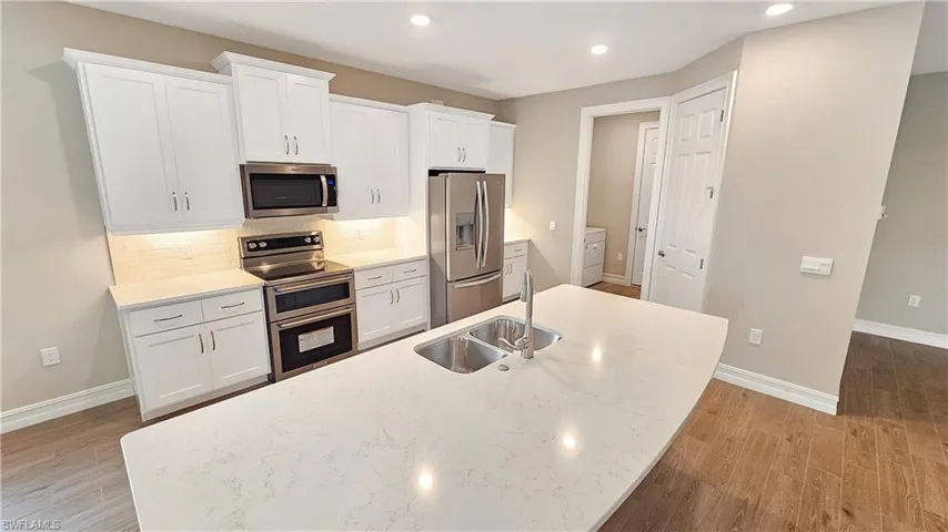 Kitchen with sink, white cabinetry, tasteful backsplash, and stainless steel appliances