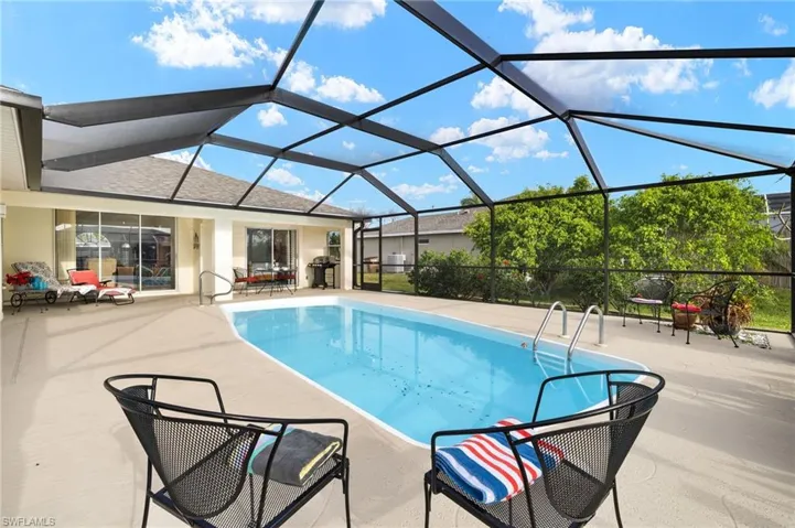 Swimming pool featuring a sunroom, a patio area, a lanai, and area for grilling