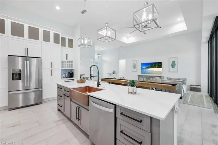 Kitchen with pendant lighting, an island with sink, sink, white cabinetry, and stainless steel appliances