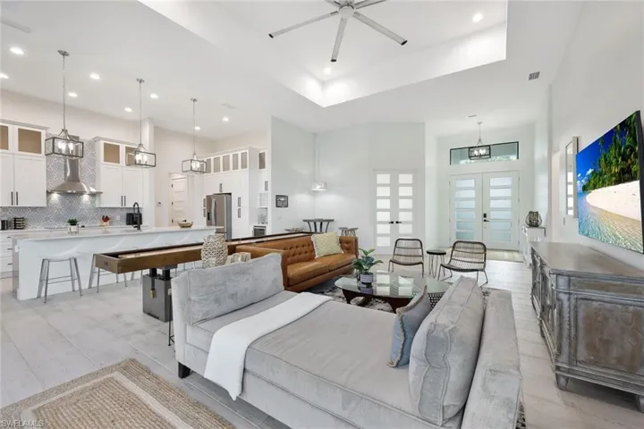 Living room with ceiling fan, a tray ceiling, and a high ceiling