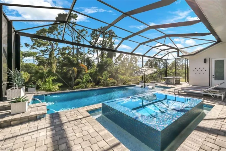 View of swimming pool featuring a lanai, pool water feature, an in ground hot tub, and a patio area