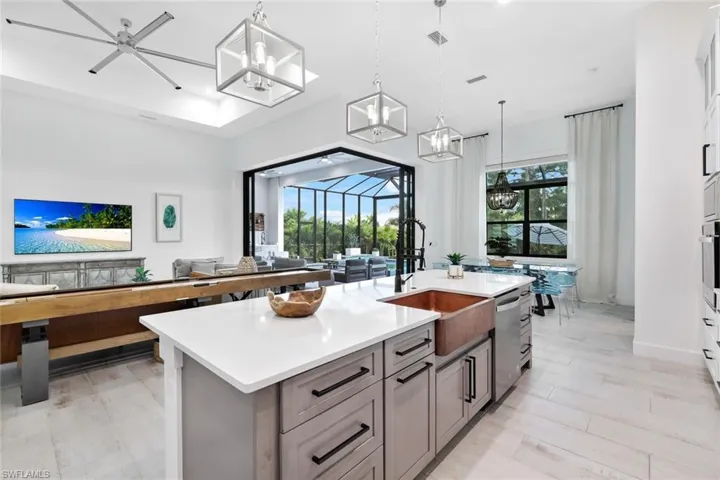 Kitchen featuring a center island with sink, hanging light fixtures, a healthy amount of sunlight, and sink