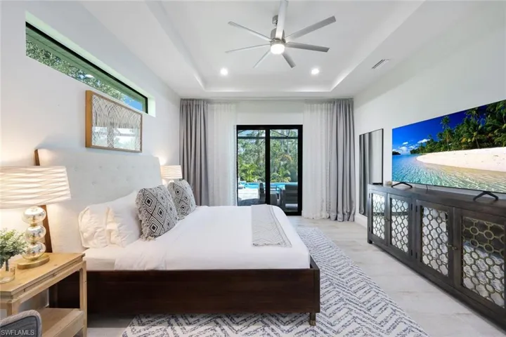 Bedroom featuring a tray ceiling, ceiling fan, and access to exterior