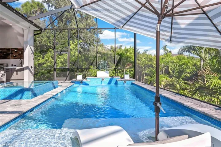 View of pool with sink, glass enclosure, a patio area, and pool water feature