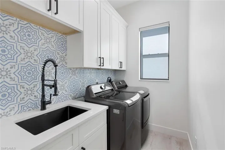 Washroom with cabinets, light hardwood / wood-style floors, sink, and independent washer and dryer