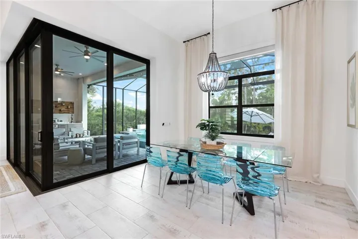 Dining space with ceiling fan with notable chandelier, a wealth of natural light, and light wood-type flooring