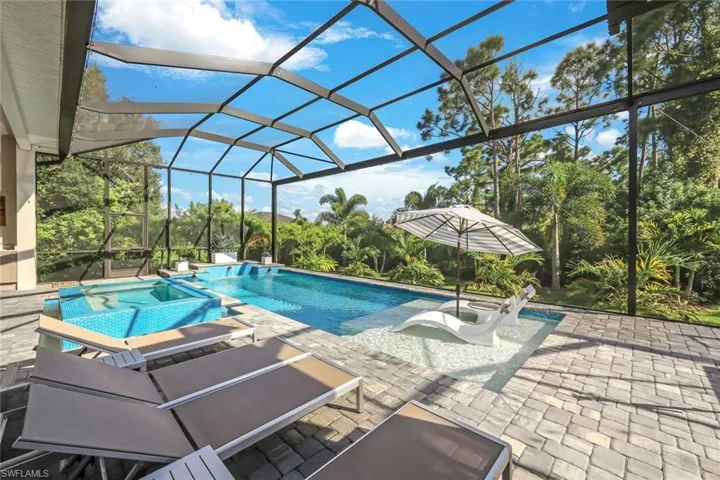 View of swimming pool with an in ground hot tub, glass enclosure, and a patio area