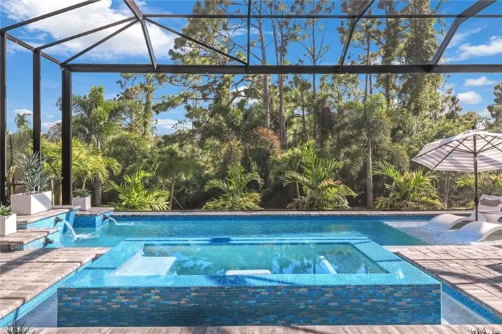 View of swimming pool with glass enclosure, an in ground hot tub, a patio, and pool water feature