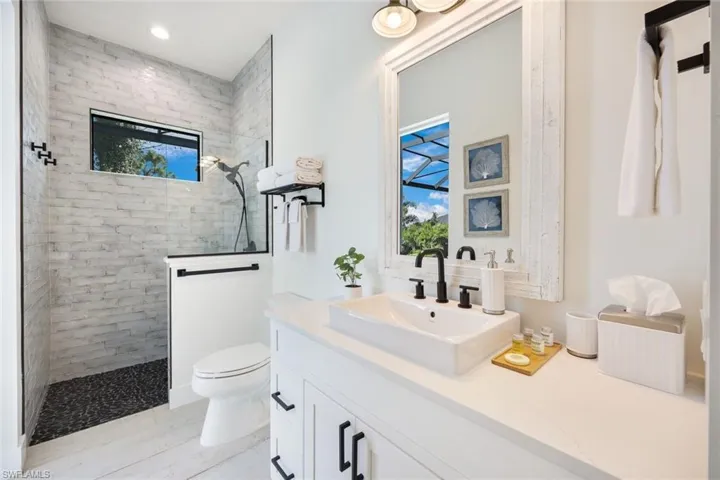 Bathroom featuring tiled shower, vanity, and plenty of natural light