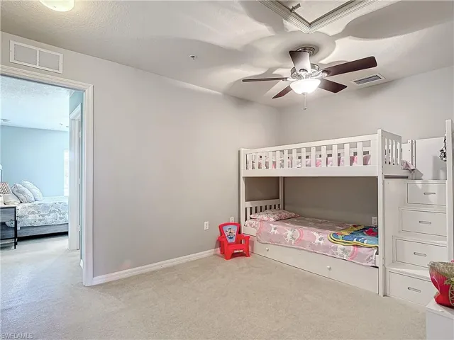 Carpeted bedroom with a textured ceiling and ceiling fan