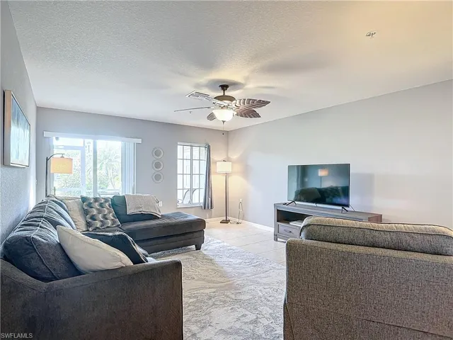Tiled living room with ceiling fan and a textured ceiling