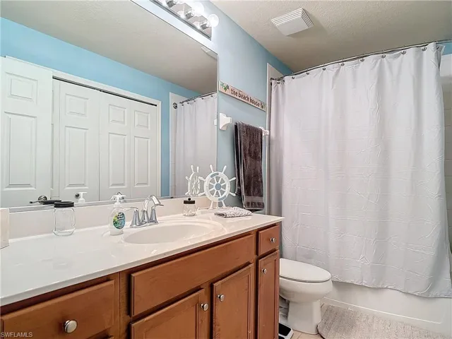 Full bathroom with toilet, tile patterned flooring, vanity, a textured ceiling, and shower / tub combo with curtain