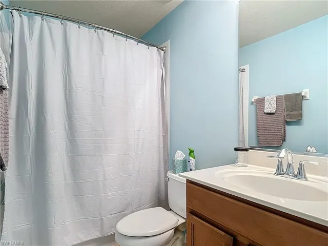 Bathroom with vanity, toilet, and a textured ceiling