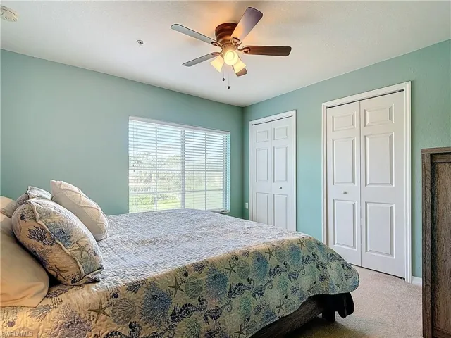 Carpeted bedroom featuring ceiling fan and two closets