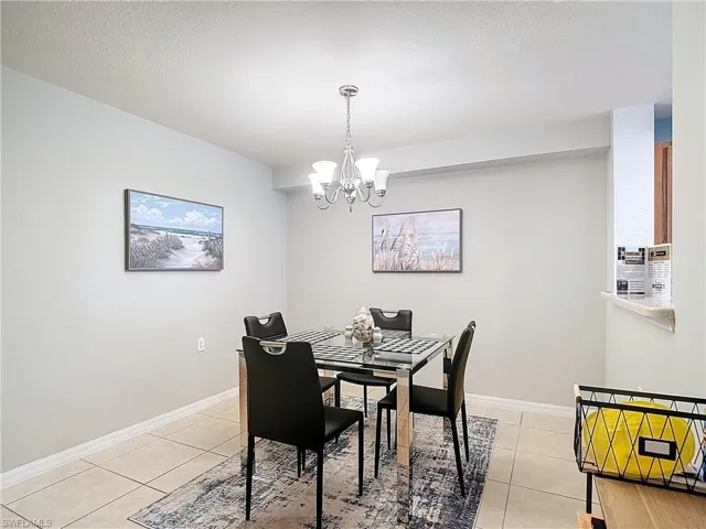 Tiled dining area featuring a notable chandelier and a textured ceiling
