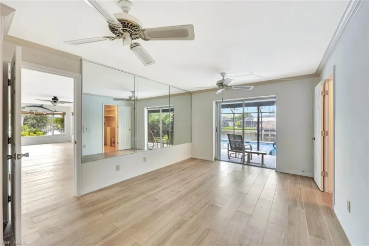 Unfurnished room featuring light wood-style flooring, a ceiling fan, baseboards, and ornamental molding