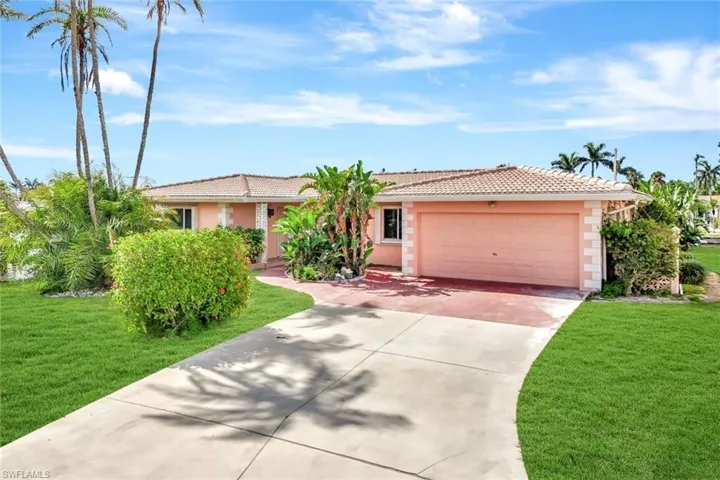 Ranch-style home featuring a tile roof, an attached garage, a front lawn, and concrete driveway