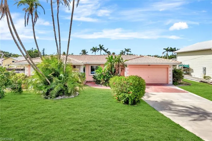 Ranch-style home with stucco siding, an attached garage, a tile roof, driveway, and a front yard