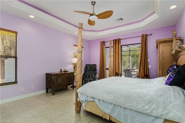 Bedroom with a raised ceiling, a ceiling fan, recessed lighting, access to exterior, and ornamental molding