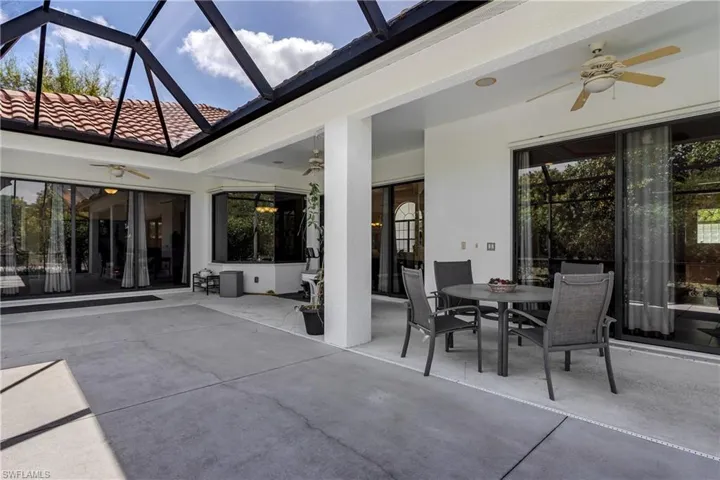 View of patio with a ceiling fan, outdoor dining area, a sunroom, and glass enclosure