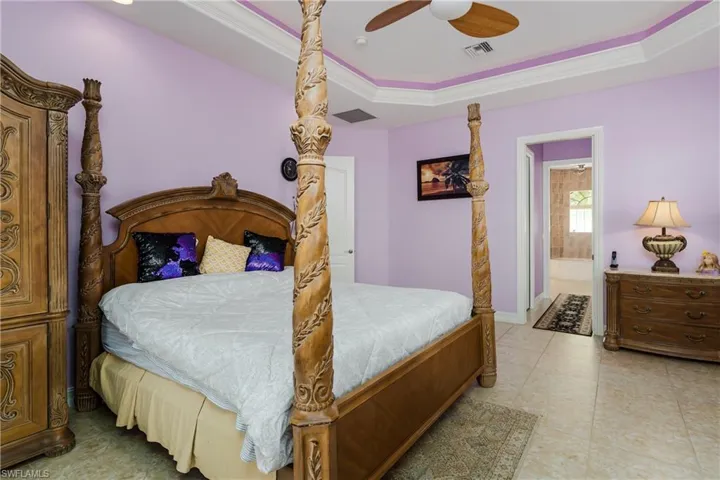 Bedroom featuring a tray ceiling, crown molding, ceiling fan, and ensuite bath