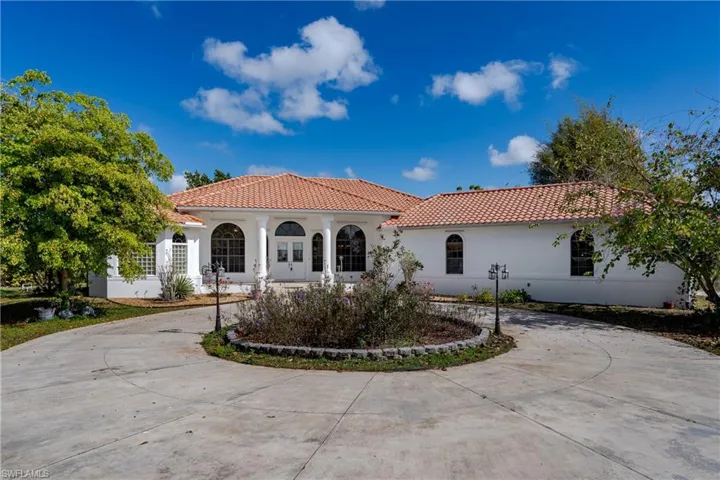 Mediterranean / spanish home with a tiled roof, stucco siding, curved driveway, and a porch