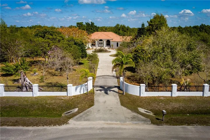 Mediterranean / spanish house featuring concrete driveway, a fenced front yard, and a gate