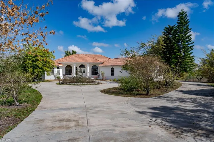 Mediterranean / spanish-style house featuring a tiled roof, stucco siding, and curved driveway