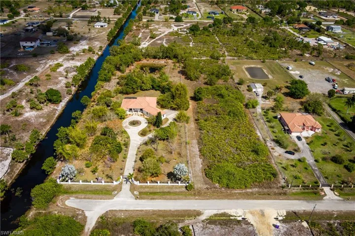 Aerial view of property and surrounding area featuring a nearby body of water and nearby suburban area