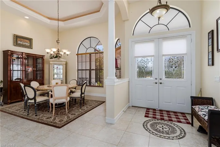 Foyer featuring hanging lights, light tile patterned floors, french doors, crown molding, and a tray ceiling
