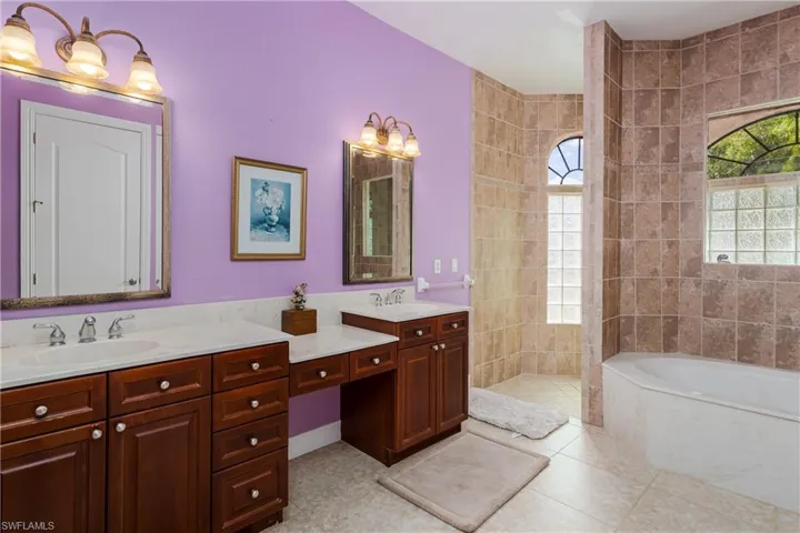 Bathroom with double vanity, a walk in shower, a garden tub, and light tile patterned floors