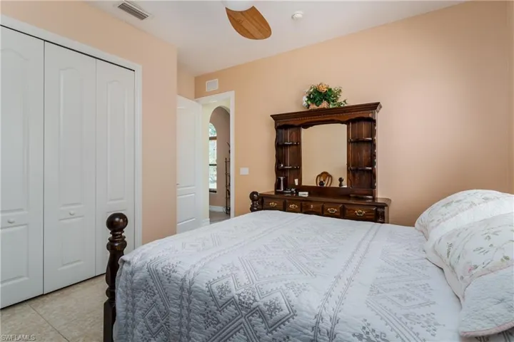 Bedroom featuring a closet, ceiling fan, arched walkways, and light tile patterned floors