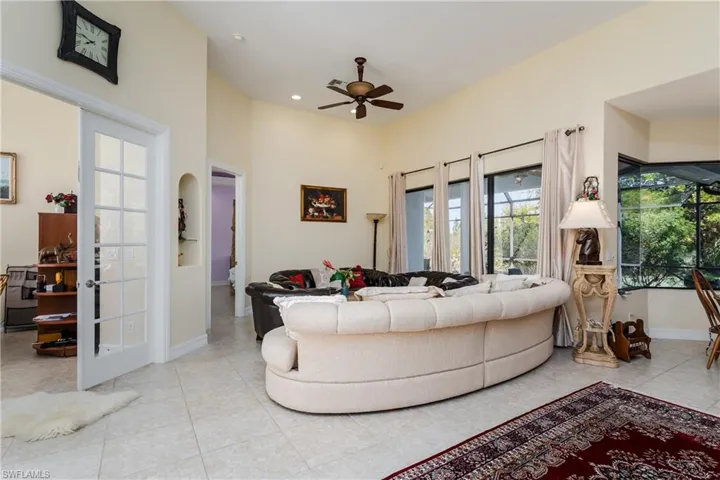 Living area featuring a ceiling fan, a high ceiling, arched walkways, and recessed lighting