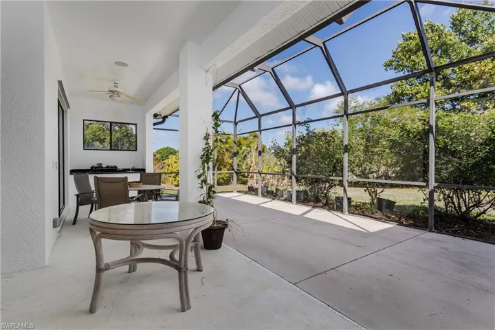 View of patio / terrace featuring a sunroom, outdoor dining space, a ceiling fan, and glass enclosure