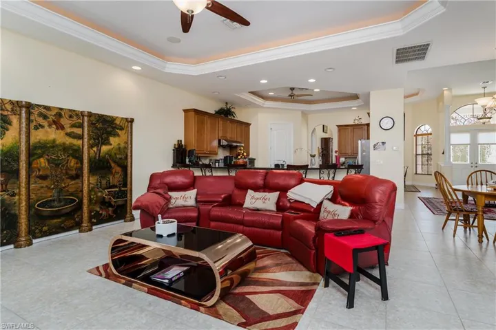 Living area featuring ceiling fan, crown molding, a raised ceiling, recessed lighting, and arched walkways