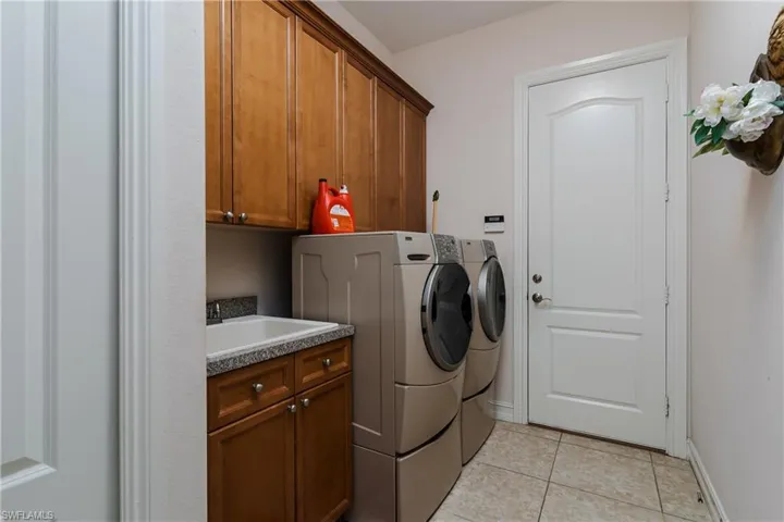 Laundry room with separate washer and dryer, light tile patterned flooring, and cabinet space