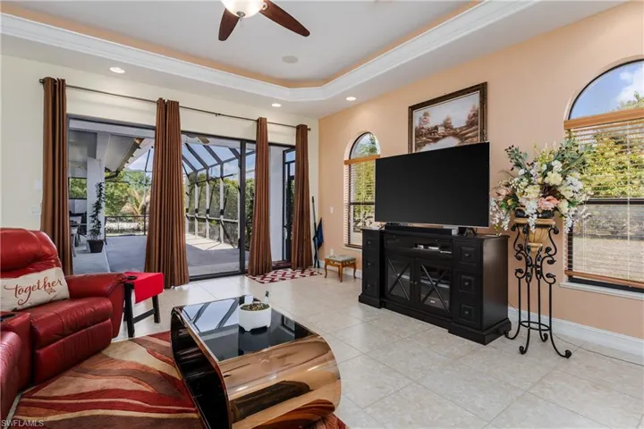 Living area featuring a ceiling fan, light tile patterned floors, a raised ceiling, and recessed lighting