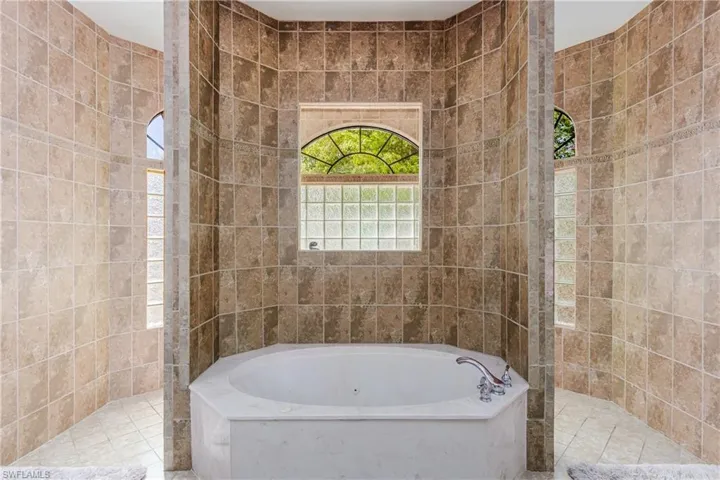 Full bathroom featuring walk in shower, a garden tub, and tile walls