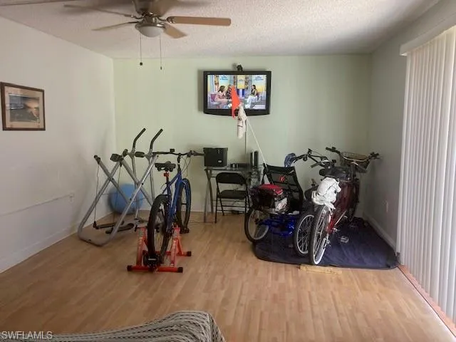 Workout area with hardwood / wood-style floors, ceiling fan, and a textured ceiling