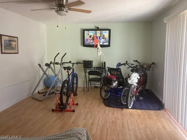 Exercise room featuring wood-type flooring, ceiling fan, and a textured ceiling