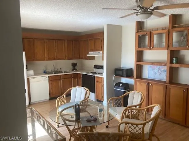 Kitchen featuring light wood-type flooring, ceiling fan, electric range, sink, and dishwasher