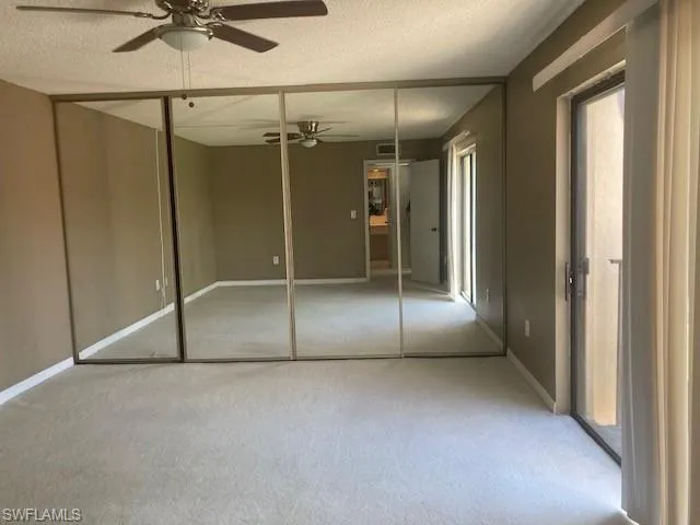 Unfurnished bedroom featuring ceiling fan, a closet, a textured ceiling, and carpet flooring