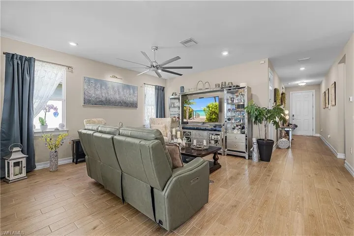 Living room with light wood-type flooring, a ceiling fan, and recessed lighting
