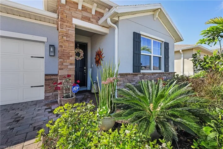 View of exterior entry with stone siding, stucco siding, and a garage