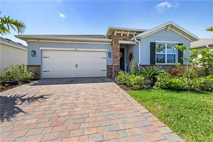 View of front of home with stone siding, stucco siding, decorative driveway, and a garage