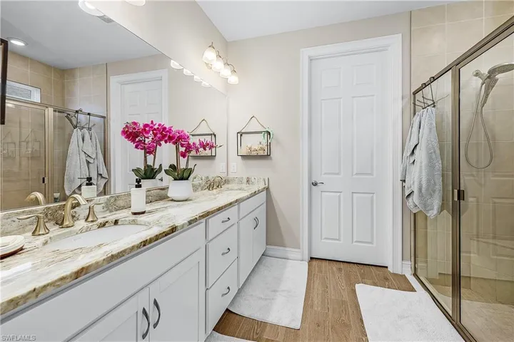 Primary bathroom with a stall shower, double vanity, and light wood-type flooring